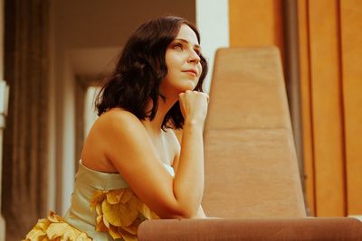 Young woman looking away while sitting at home