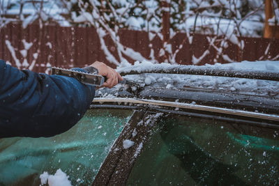 Young teen cleaning snow from the back of the car