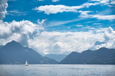 Sailboat sailing in sea against mountains