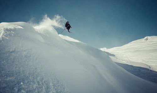 Low angle view of people skiing on snow covered mountain