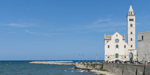 View of building by sea against blue sky