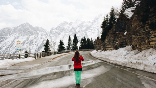 Woman standing on road against mountains during winter