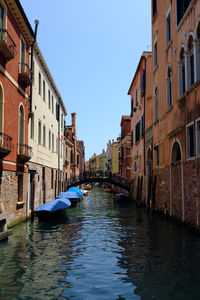 Boats moored in grand canal amidst old buildings against clear sky