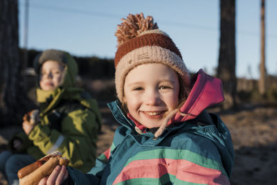 Portrait of a young girl eating a hot dog by a campfire in sweden