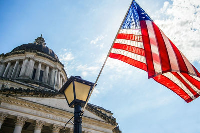 Low angle view of flag and buildings against sky