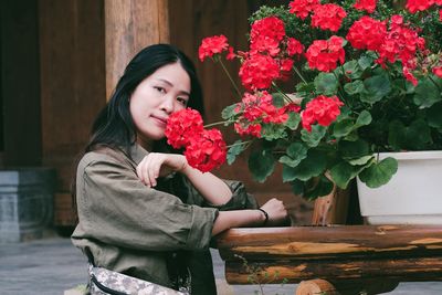 Portrait of young woman sitting by flowers