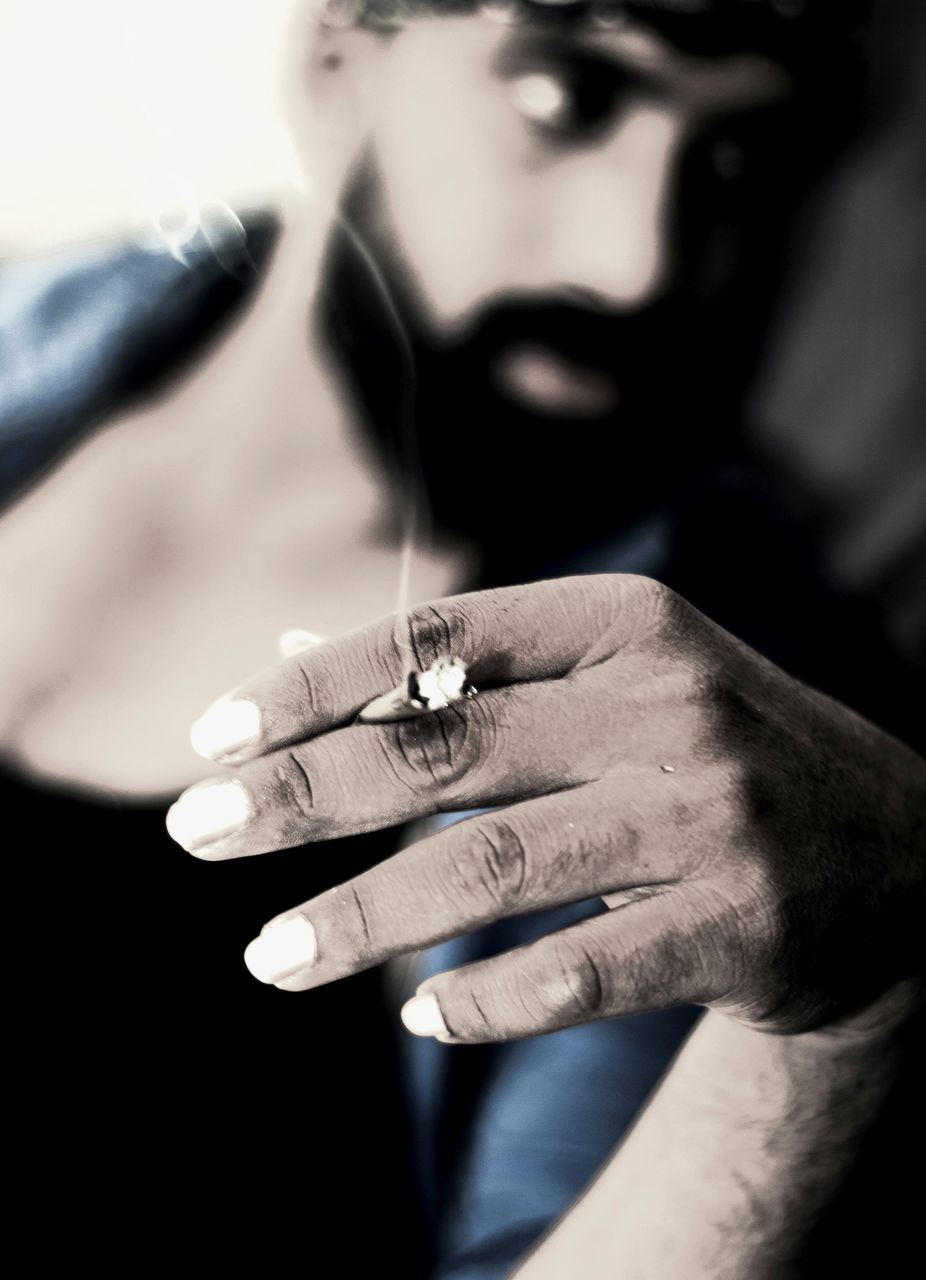 CLOSE-UP OF MAN SMOKING CIGARETTE OUTDOORS