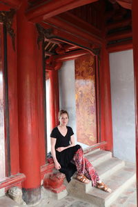 Full length portrait of woman sitting on steps at temple