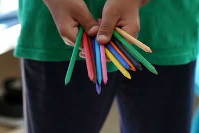 Midsection of woman holding multi colored paper