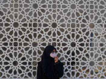 Portrait of young woman standing against wall