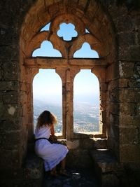 Woman looking through old building window