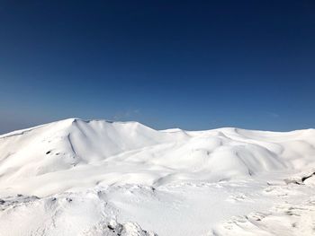 Scenic view of snowcapped mountains against clear blue sky