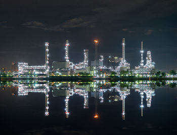 Illuminated factory against sky at night