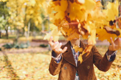 Woman throwing maple leaves in park