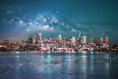 Illuminated cityscape by sea against sky at night