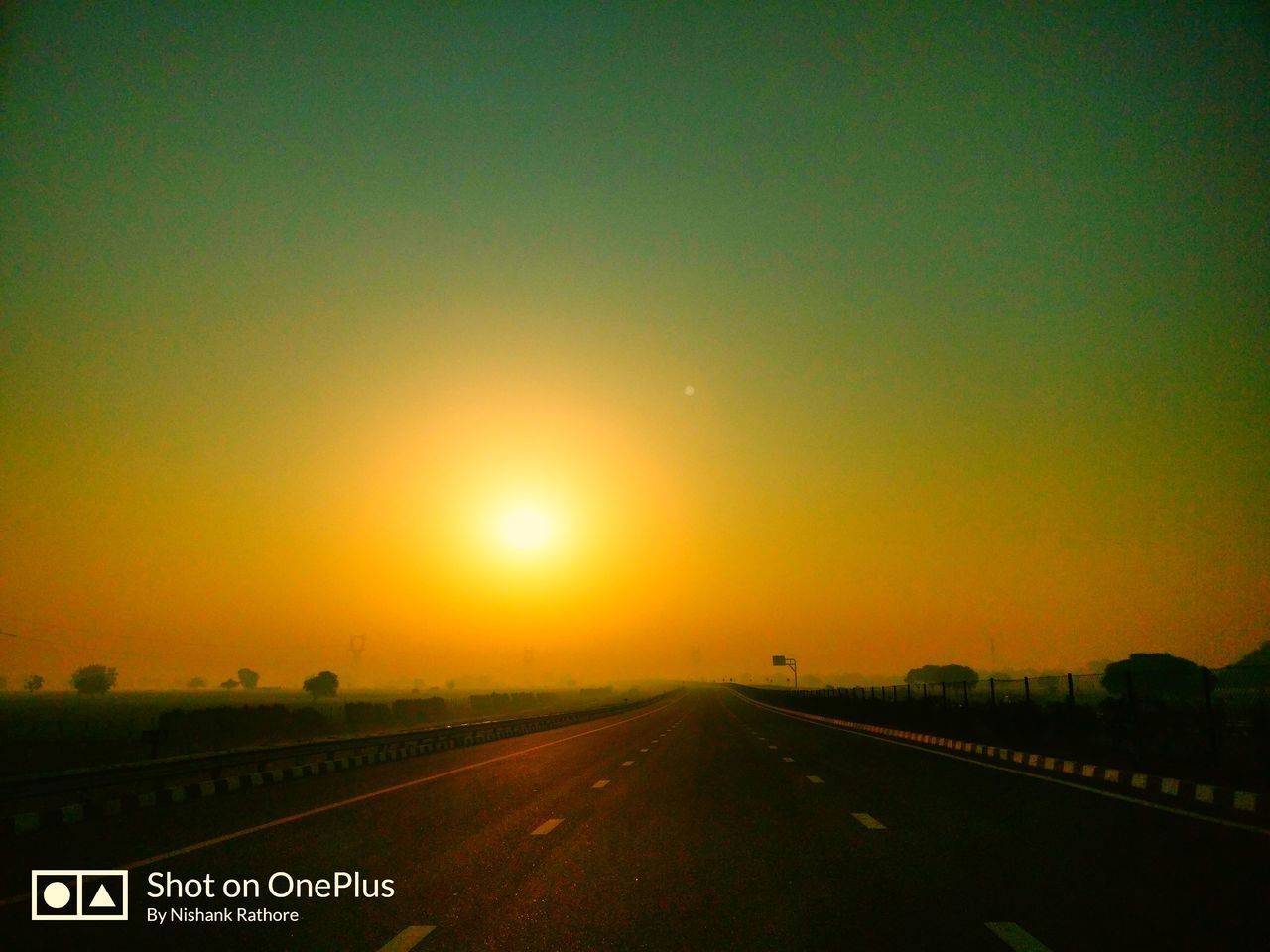 ROAD PASSING THROUGH LANDSCAPE AGAINST SUNSET