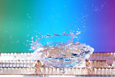 Close-up of water splashing on gemstone against multi colored background