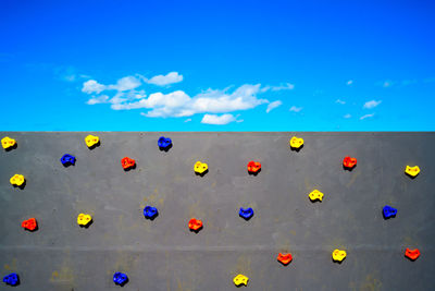 Multi colored climb holds on wall against bright blue sky