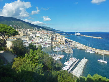 High angle view of cityscape by sea against blue sky