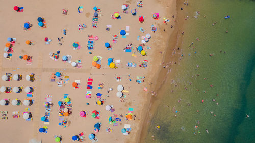 Aerial view of sandy beach with tourists swimming in beautiful clear sea water in madeira island.