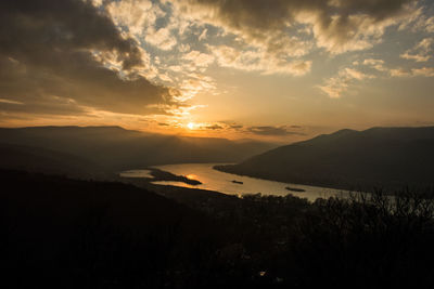 Scenic view of silhouette mountains and river against sky during sunset