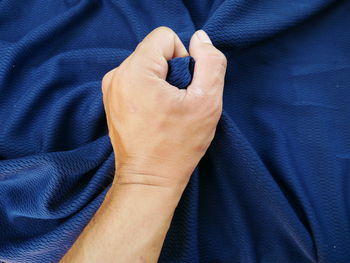 Cropped hand holding crumpled bed sheet