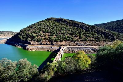 Scenic view of river by mountains against clear sky