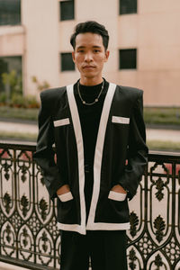 Portrait of young man standing against building