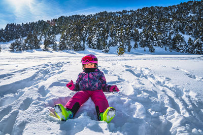 Smiling girl sitting on fresh snow with mountains and forest in a background, andorra