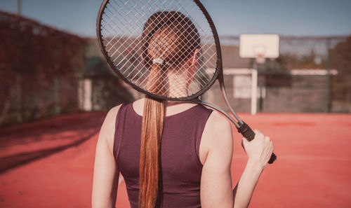 Rear view of woman holding tennis racket