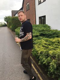 Young man standing by tree against sky