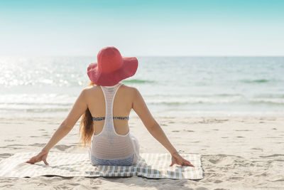 Rear view of shirtless man sitting on beach