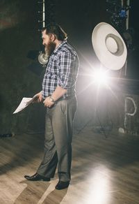 Man holding paper while standing in illuminated room