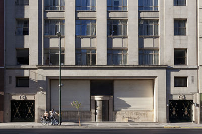 Men sitting on motorcycle against buildings during sunny day