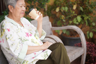 Young woman drinking water while sitting on bench