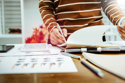 Midsection of woman reading book on table