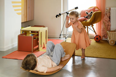 Child playing on balance board for toddlers in kids room. curvy rocker board used for motor physical