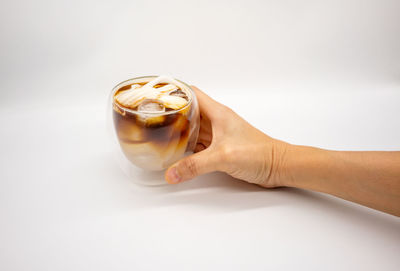 Close-up of hand holding glass against white background