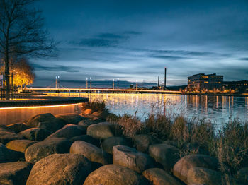 Rocks by river against sky at dusk