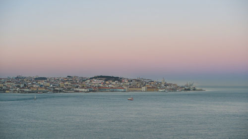 Scenic view of sea by buildings against sky during sunset