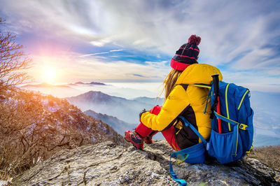 Rear view of woman sitting on rock