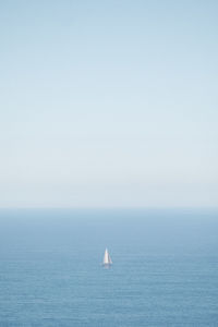 Sailboat in sea against clear sky