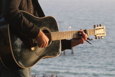 Close-up of man playing guitar at beach