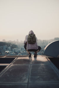 Rear view of man crouching on built structure