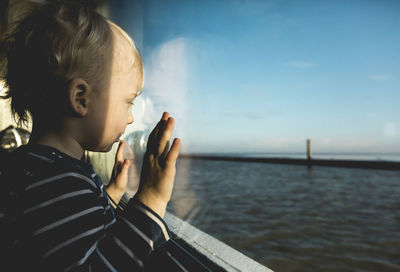 Side view of boy looking at sea against sky