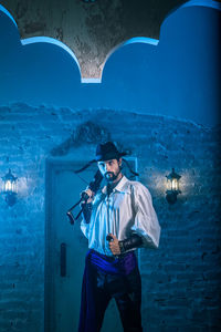 Portrait of man in costume standing against door of abandoned building at night