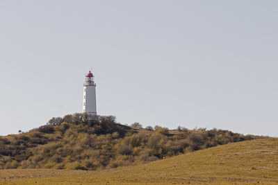 Lighthouse on field by building against clear sky
