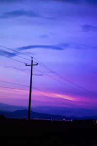 Silhouette electricity pylon against romantic sky at sunset