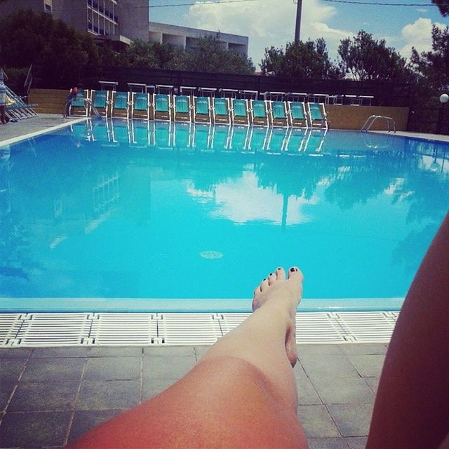 low section, person, swimming pool, water, personal perspective, lifestyles, barefoot, leisure activity, blue, human foot, relaxation, sunlight, poolside, part of, high angle view, unrecognizable person