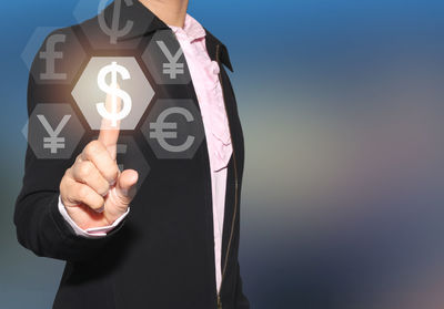 Digital composite image of businessman touching currency symbols on device screen